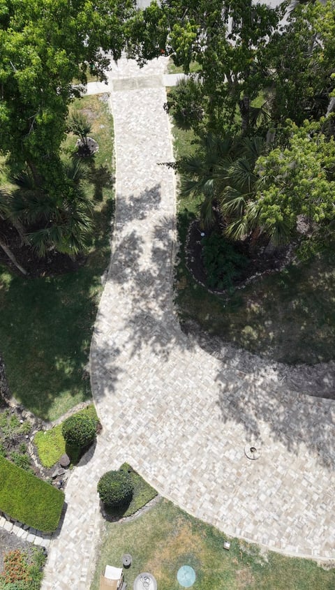 Aerial view of a winding stone paver pathway through green vegetation and landscaped gardens
